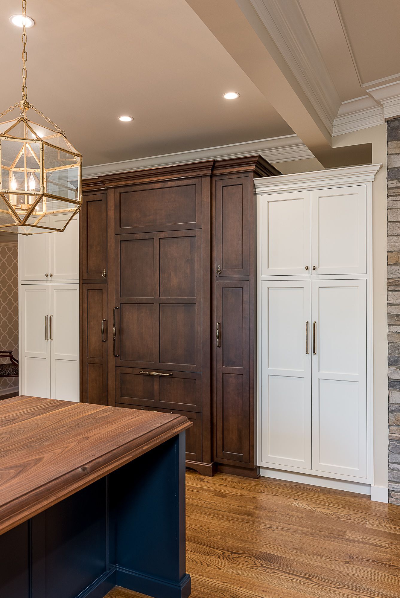 A kitchen with wooden cabinets and white cabinets and a large island.