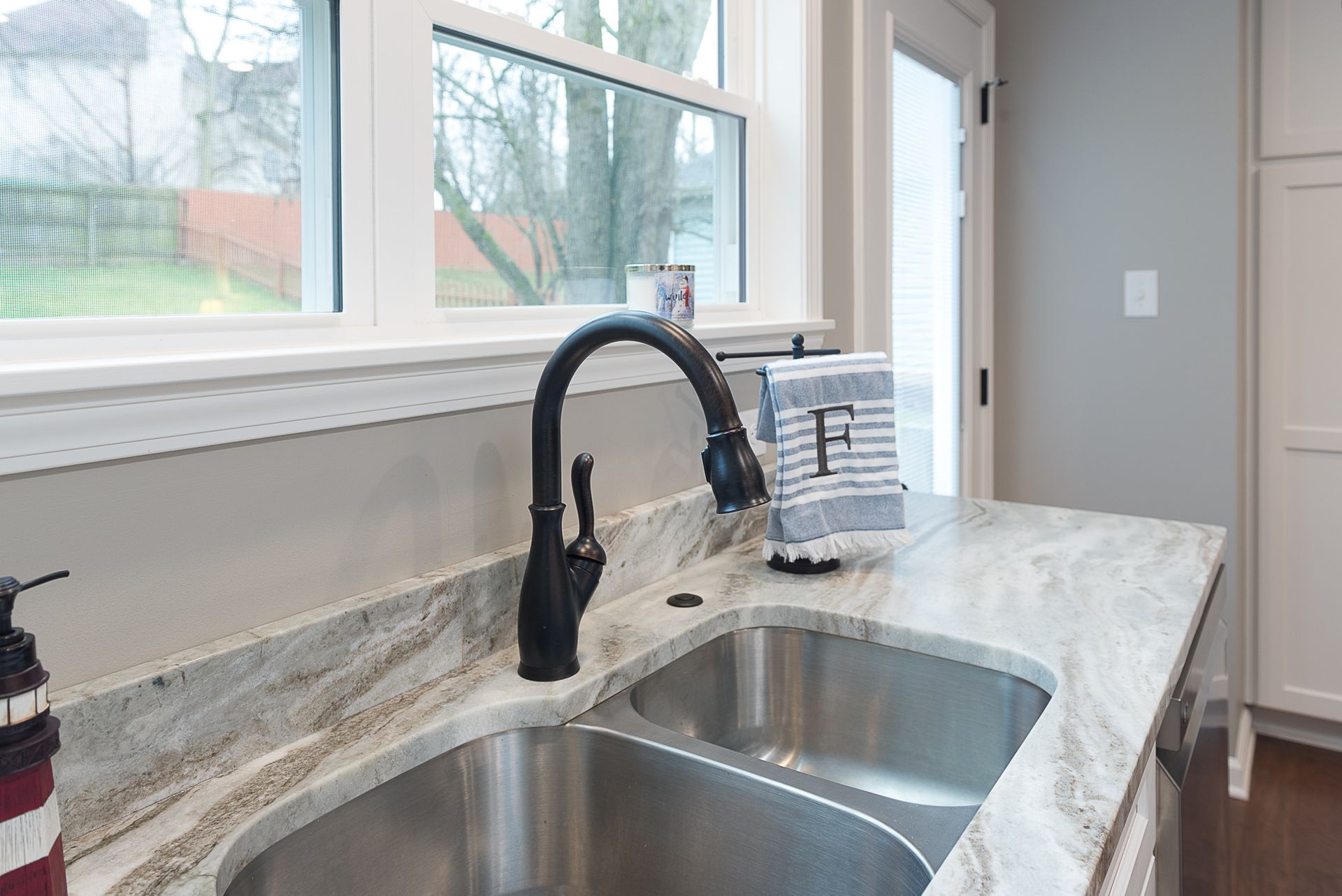 A kitchen sink with a black faucet and a window in the background.