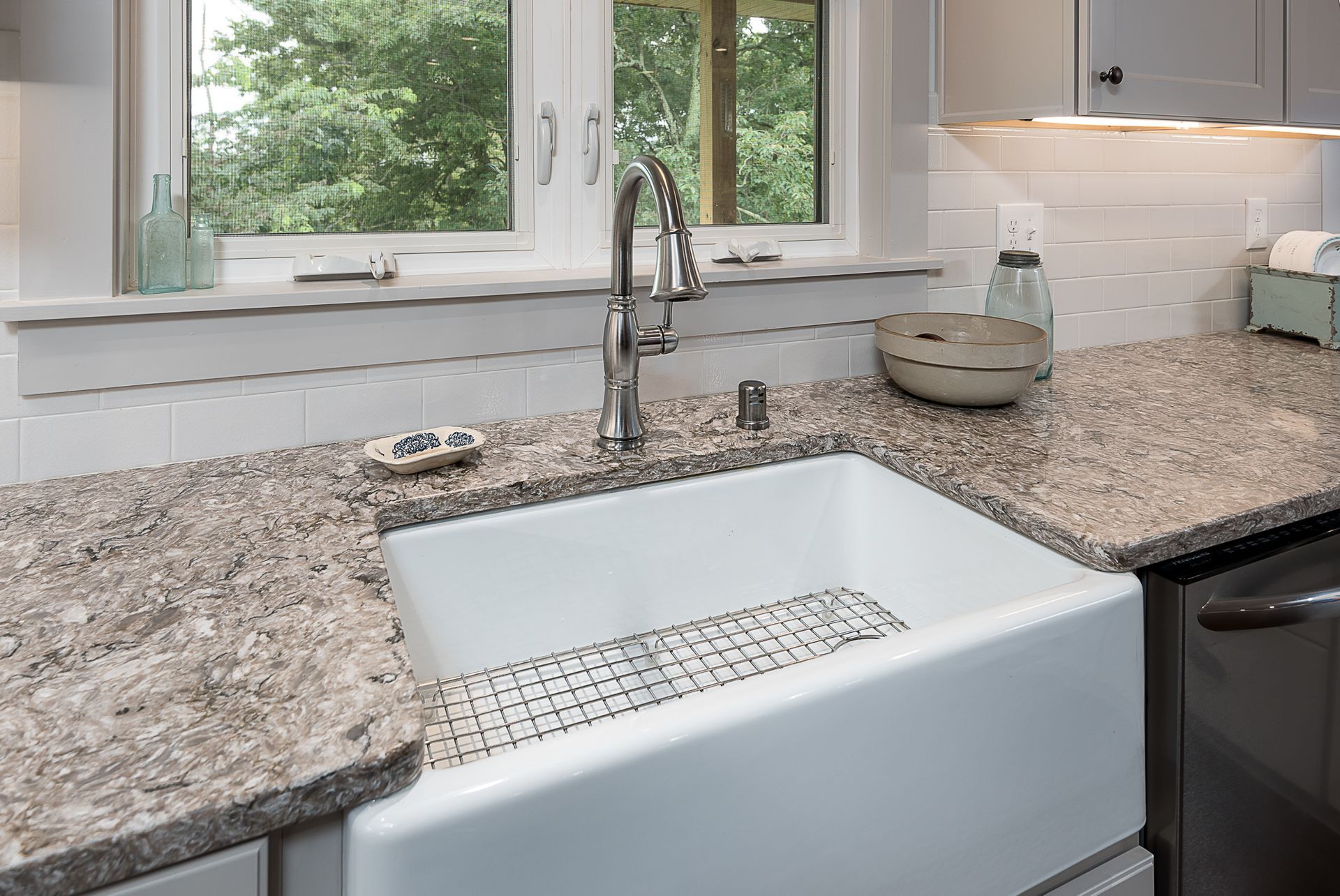 A kitchen with a white farmhouse sink and granite counter tops.