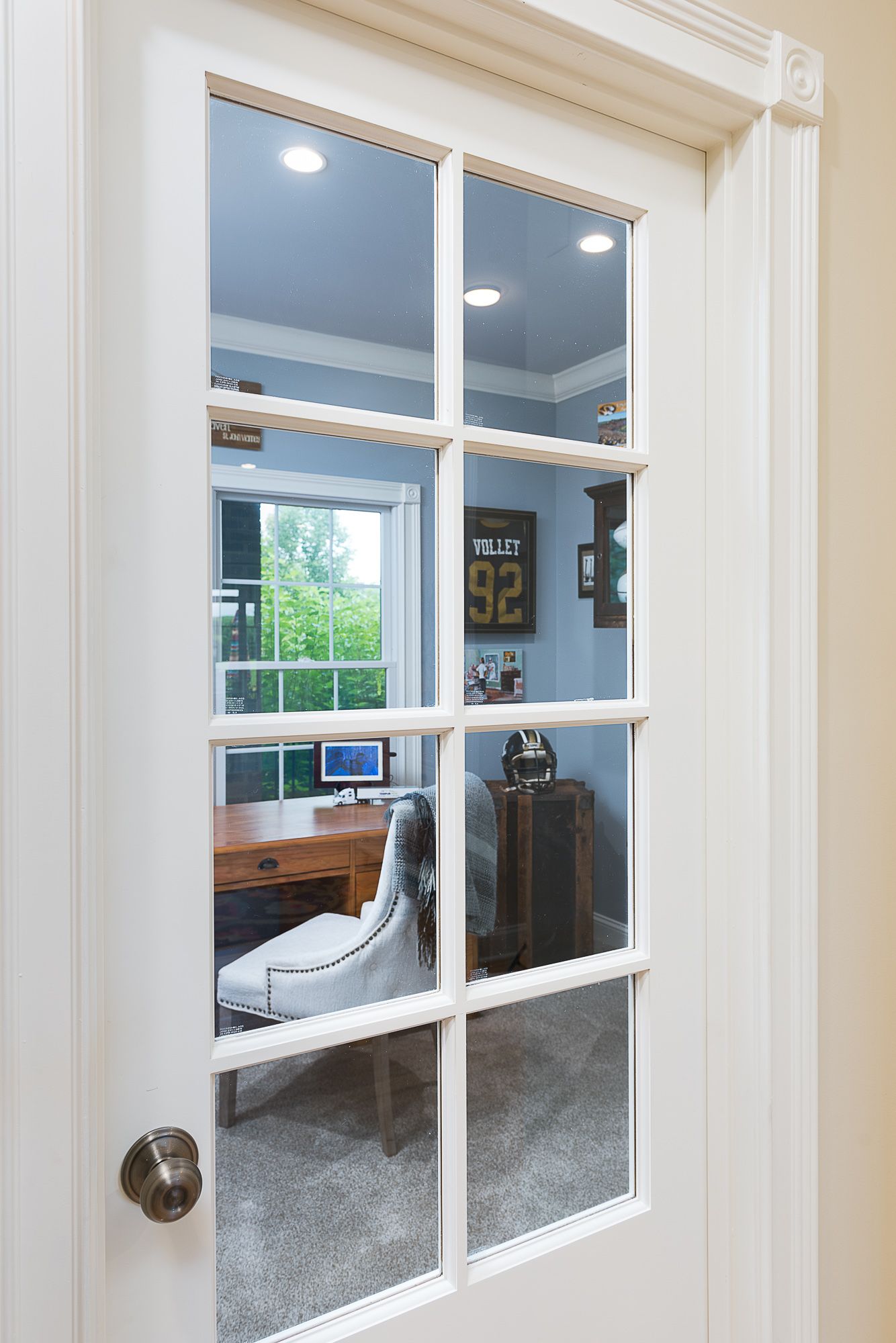 A french door is open to a room with a desk and chair.