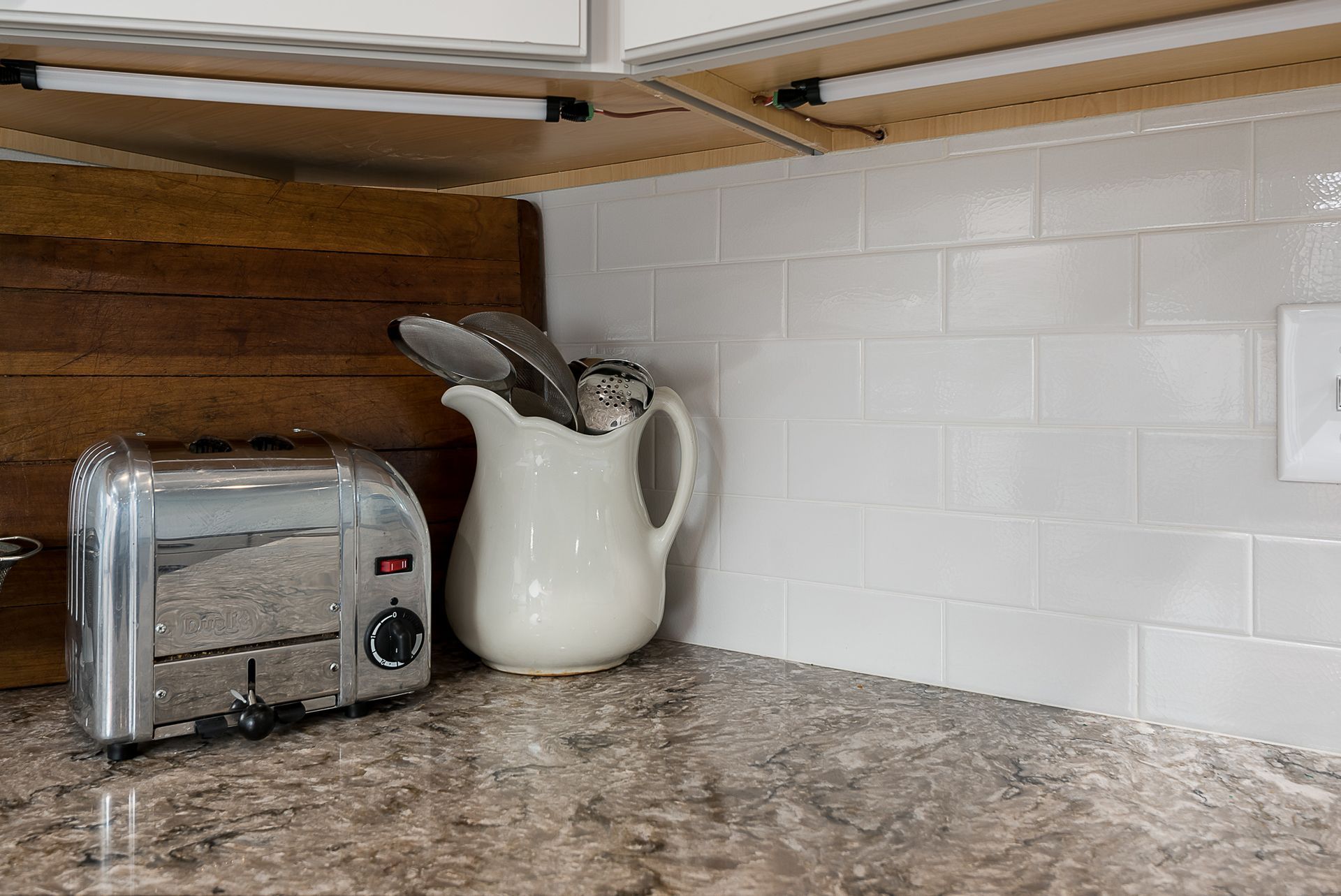 A toaster and a pitcher are on a kitchen counter.