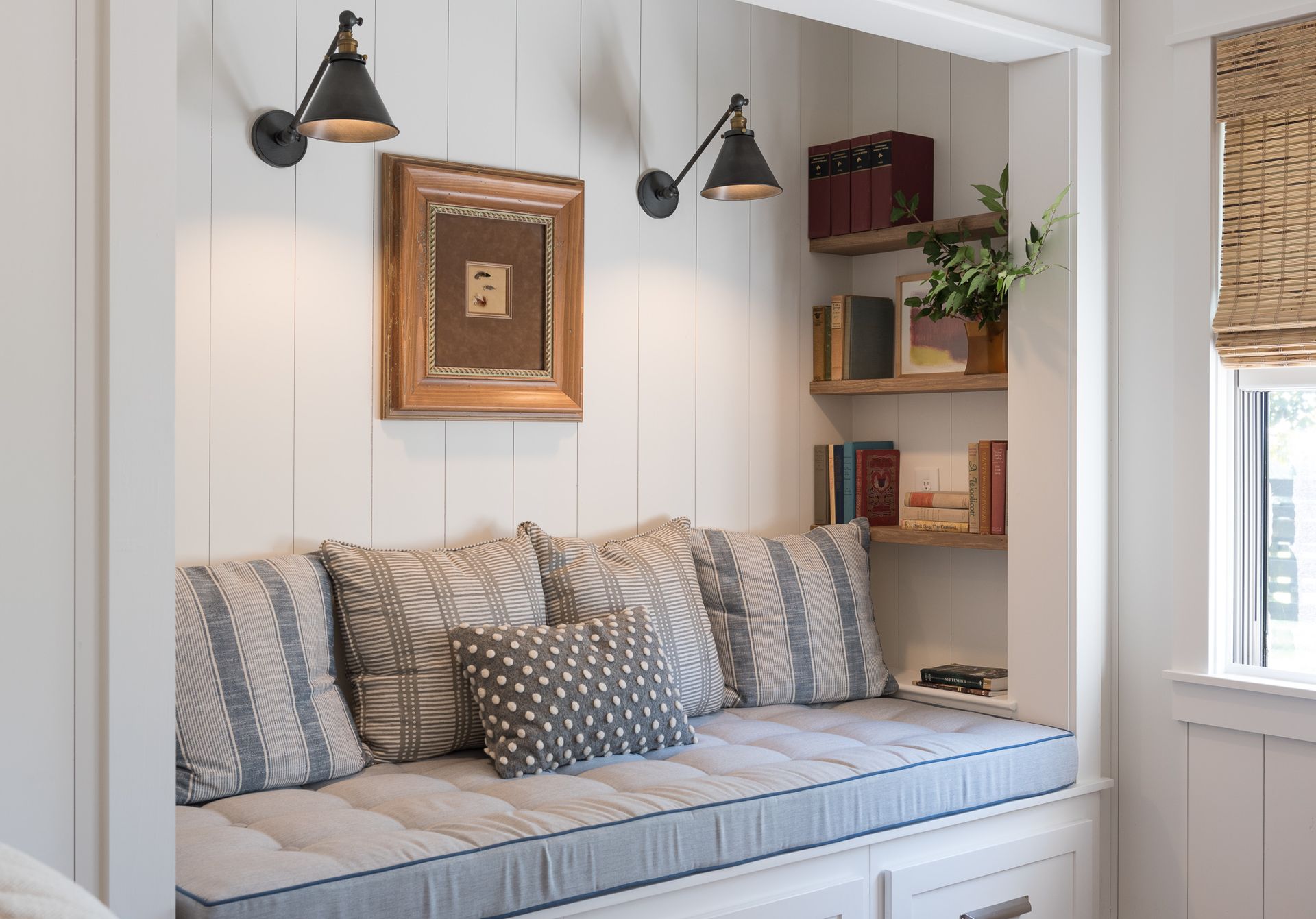There is a couch in the corner of the room with pillows on it.