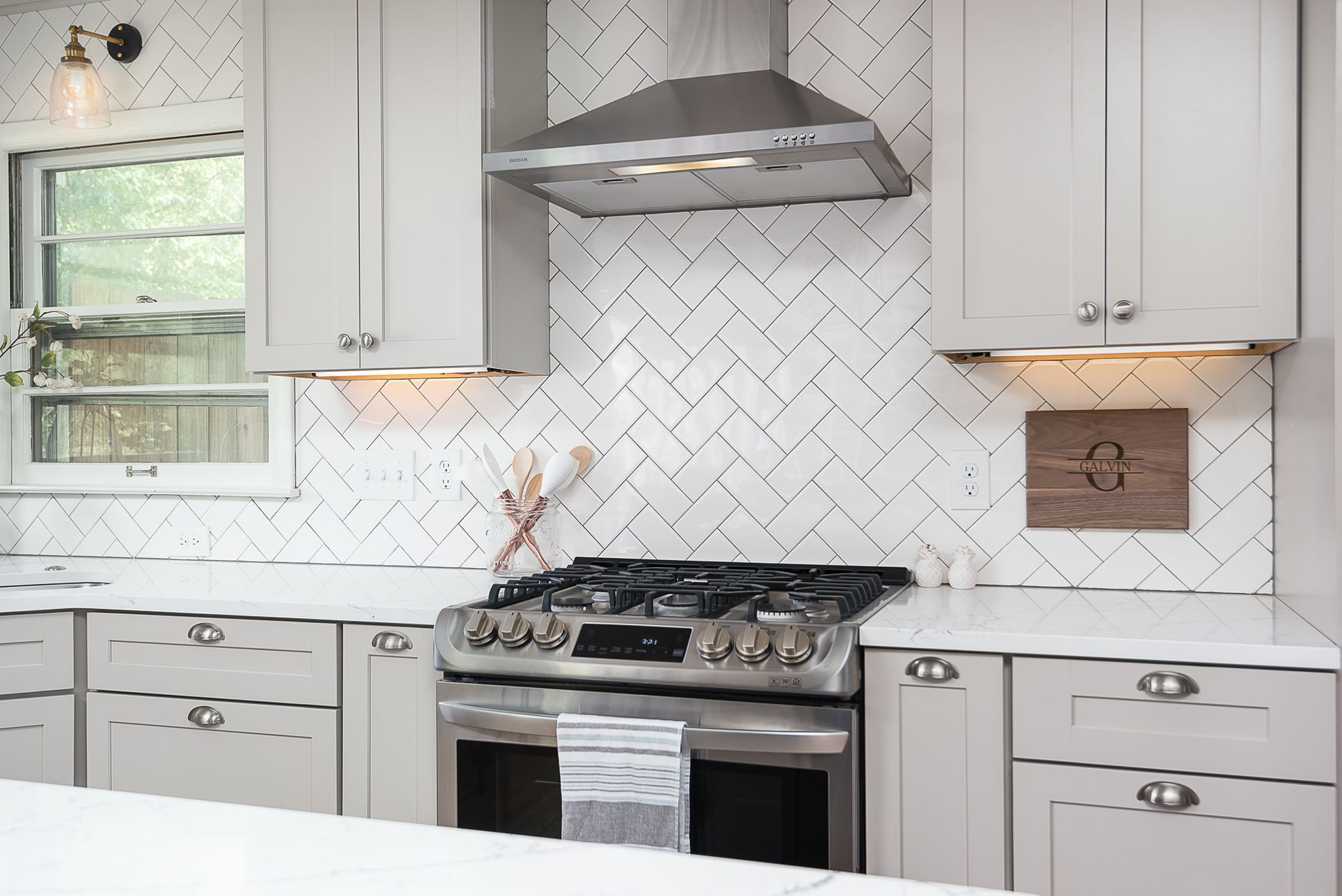 A kitchen with white cabinets , a stove , and a hood.