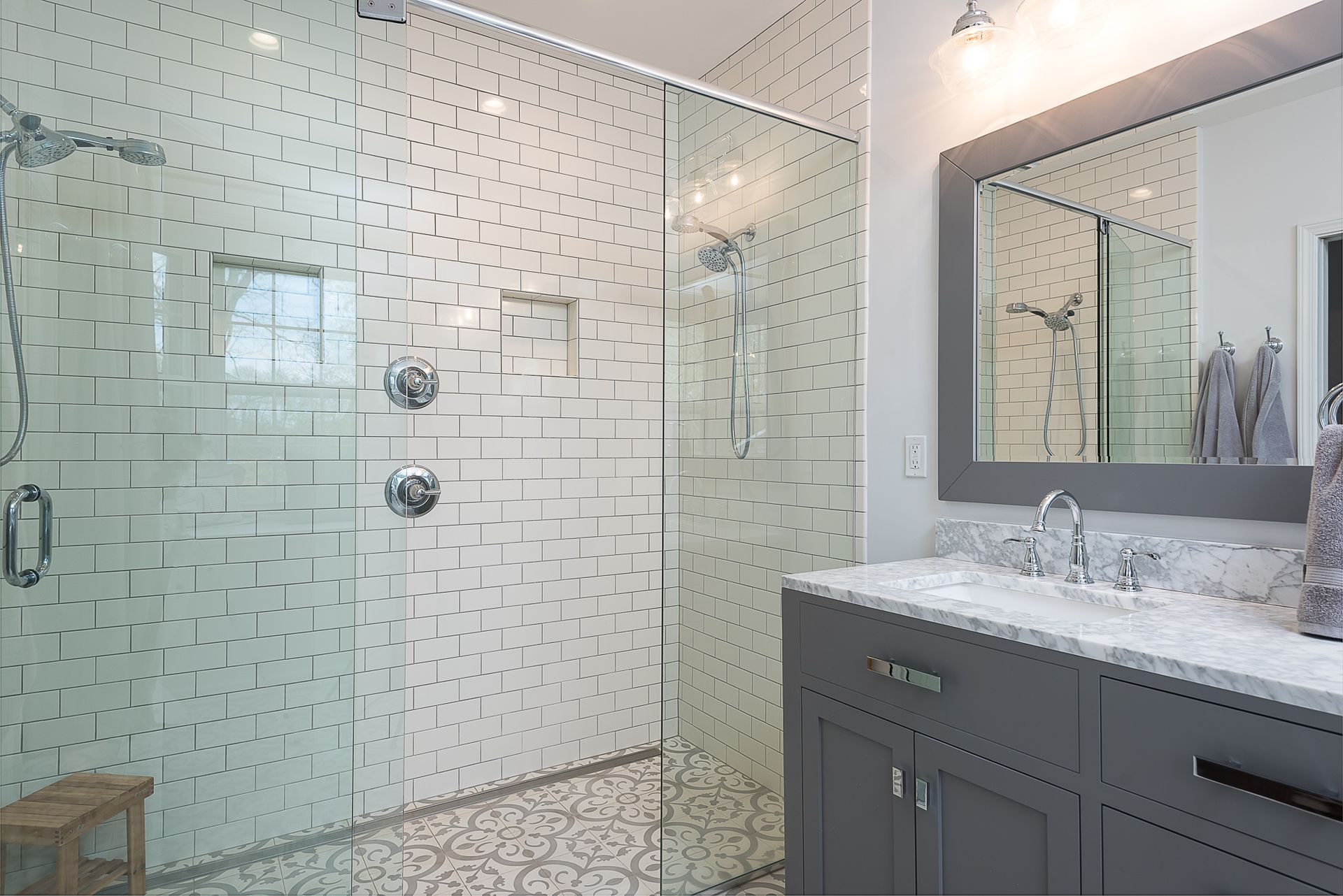 A bathroom with a walk in shower , sink and mirror.