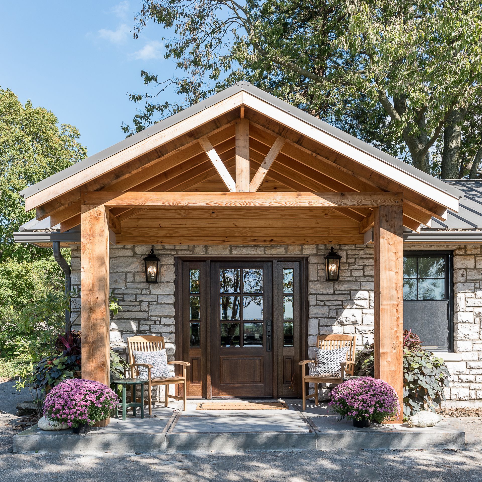 A stone house with a wooden porch and chairs