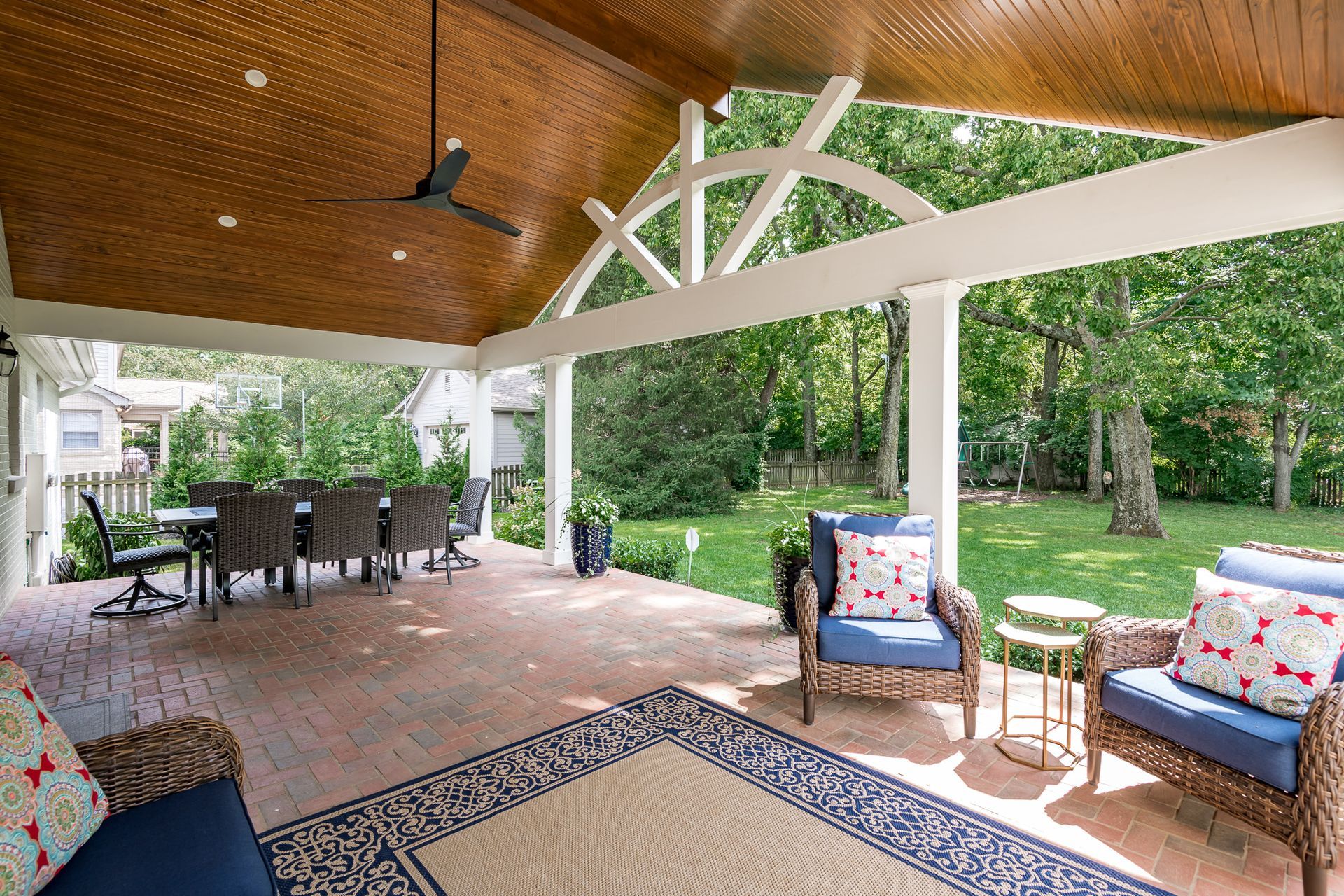 A patio with a ceiling fan , chairs , a table and a rug.