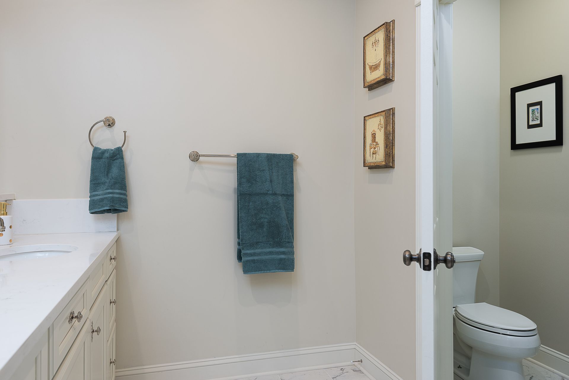 A bathroom with a toilet , sink , and towels hanging on the wall.