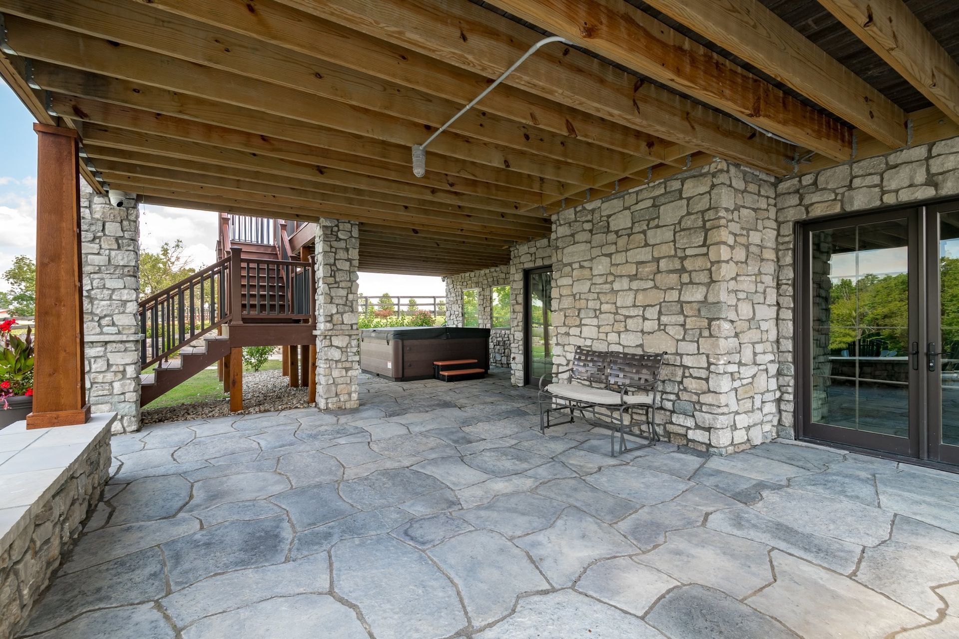 A large patio with a wooden deck and a stone wall.