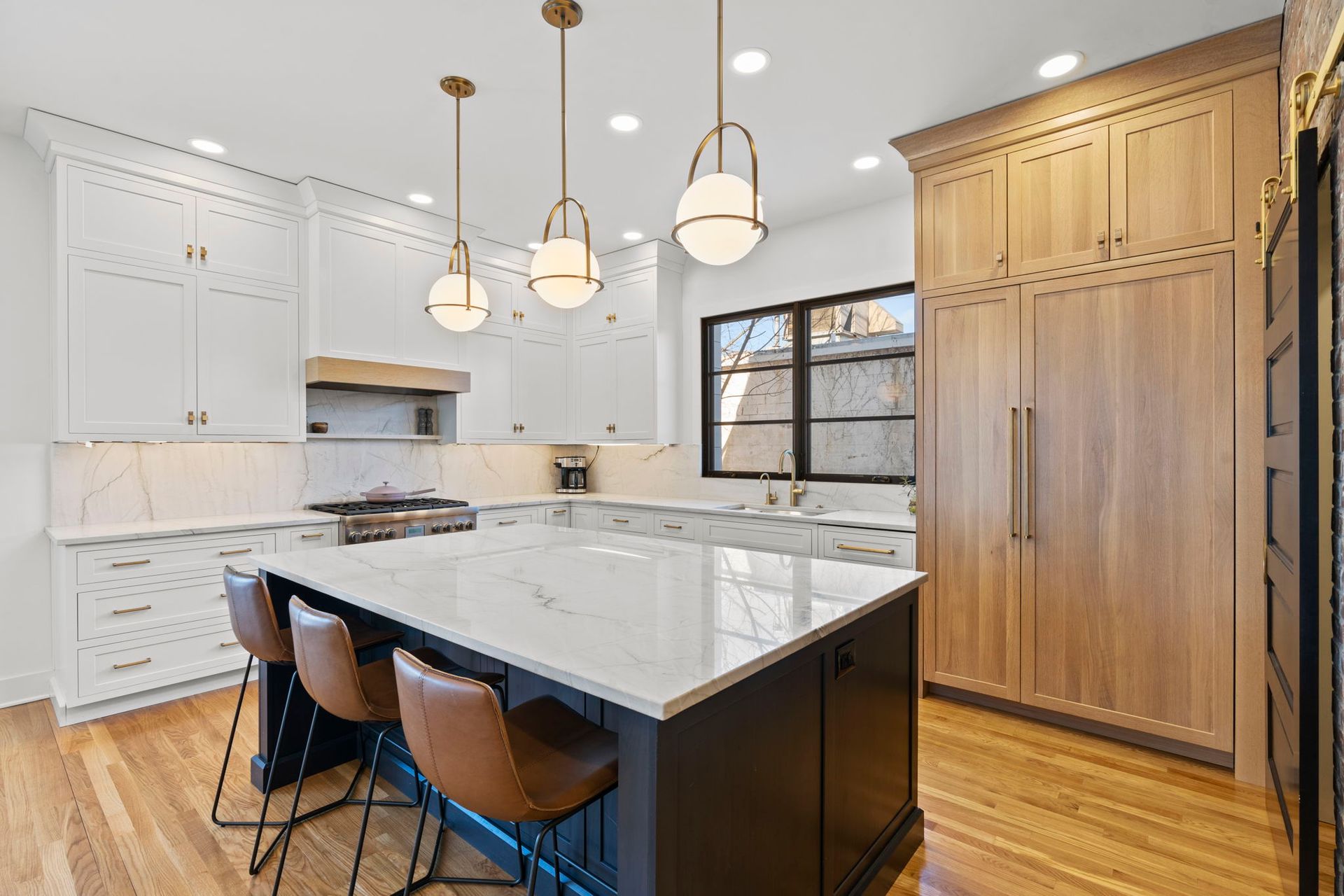 A kitchen with white cabinets and wooden floors and a large island.