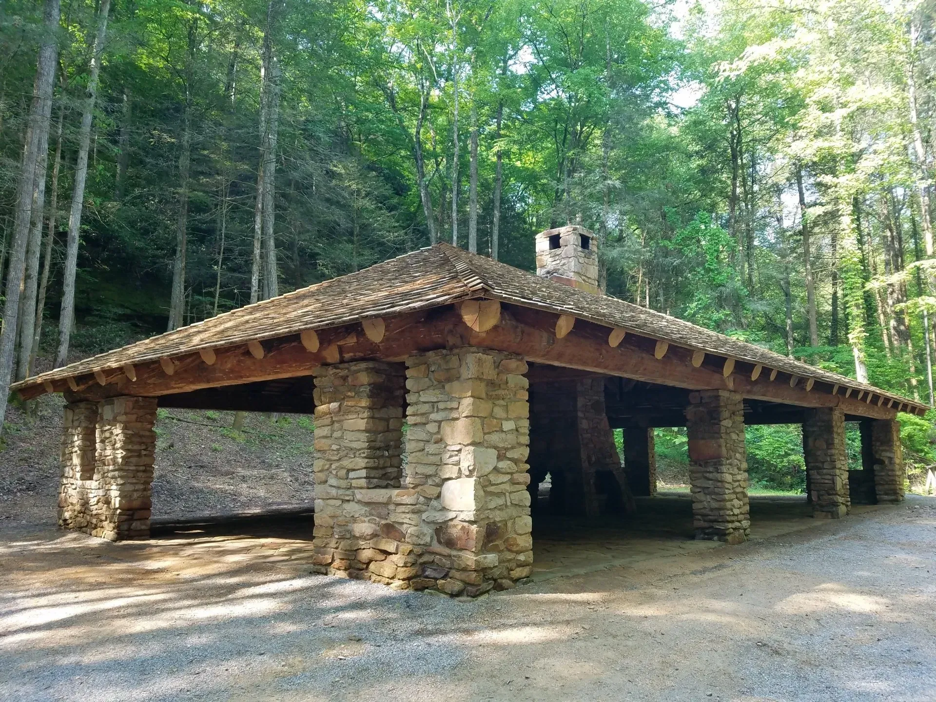 A stone building with a wooden roof in the middle of a forest
