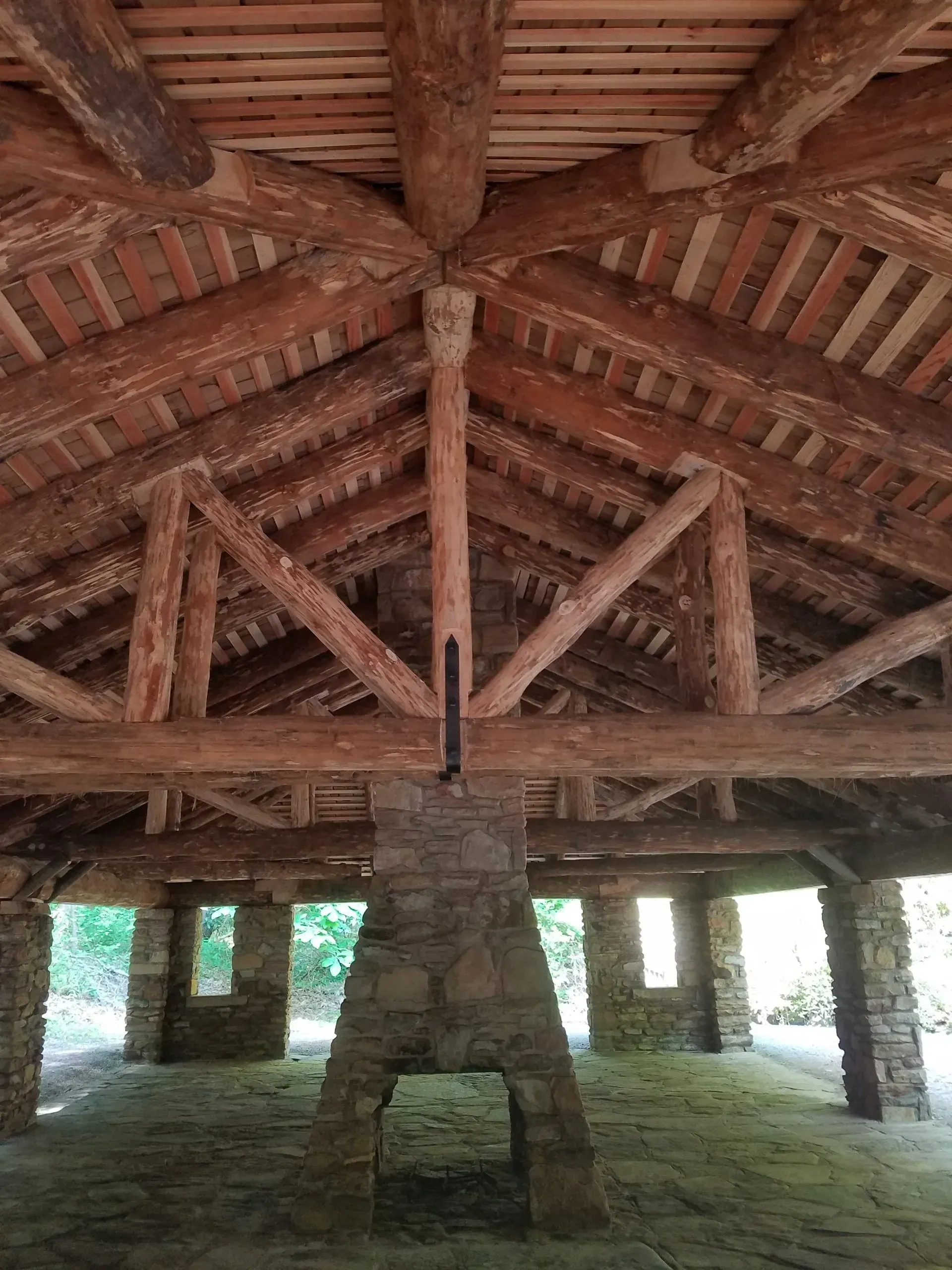 The inside of a building with wooden beams and a chimney.