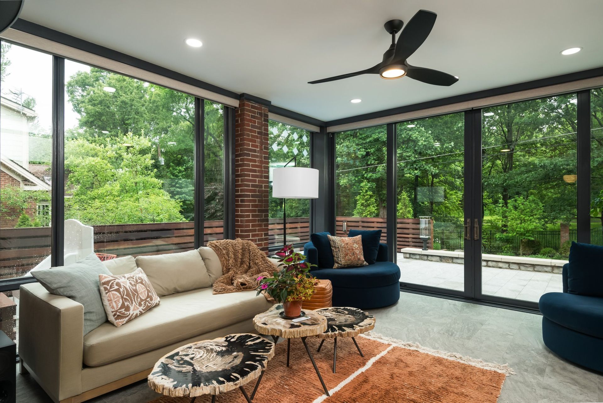 A living room with a couch , chairs , tables and a ceiling fan.
