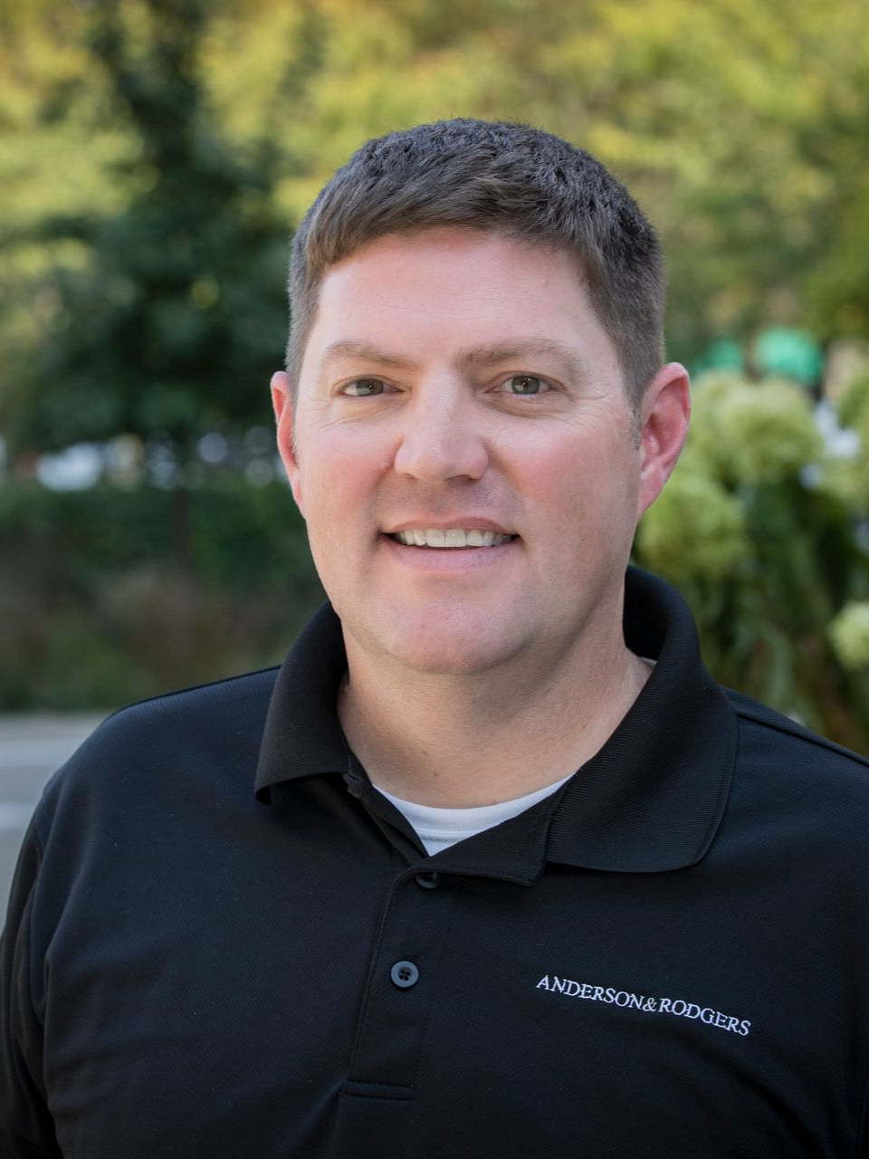 A man wearing a carhartt vest is smiling for the camera.