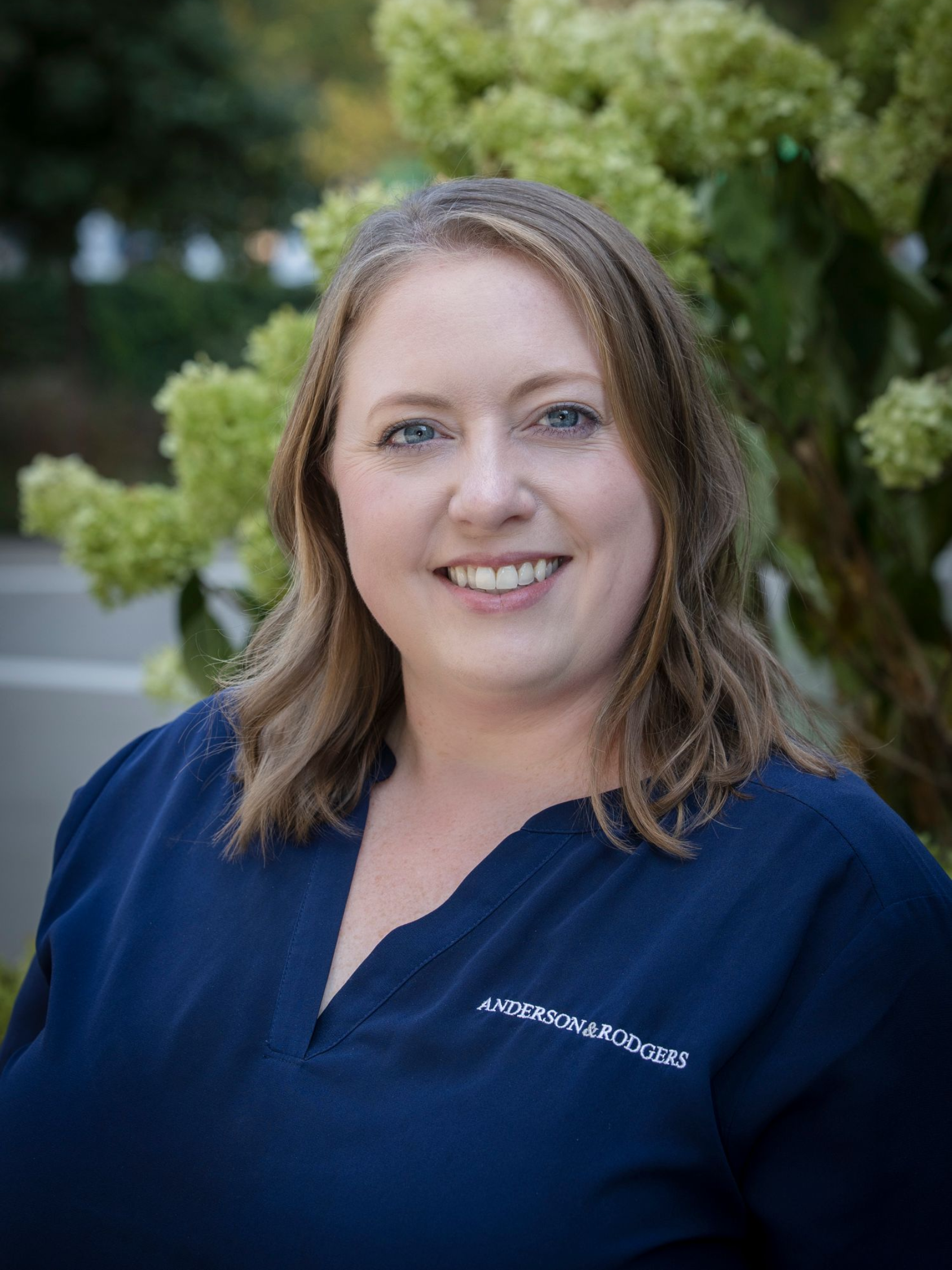 A woman in a blue shirt is smiling for the camera.