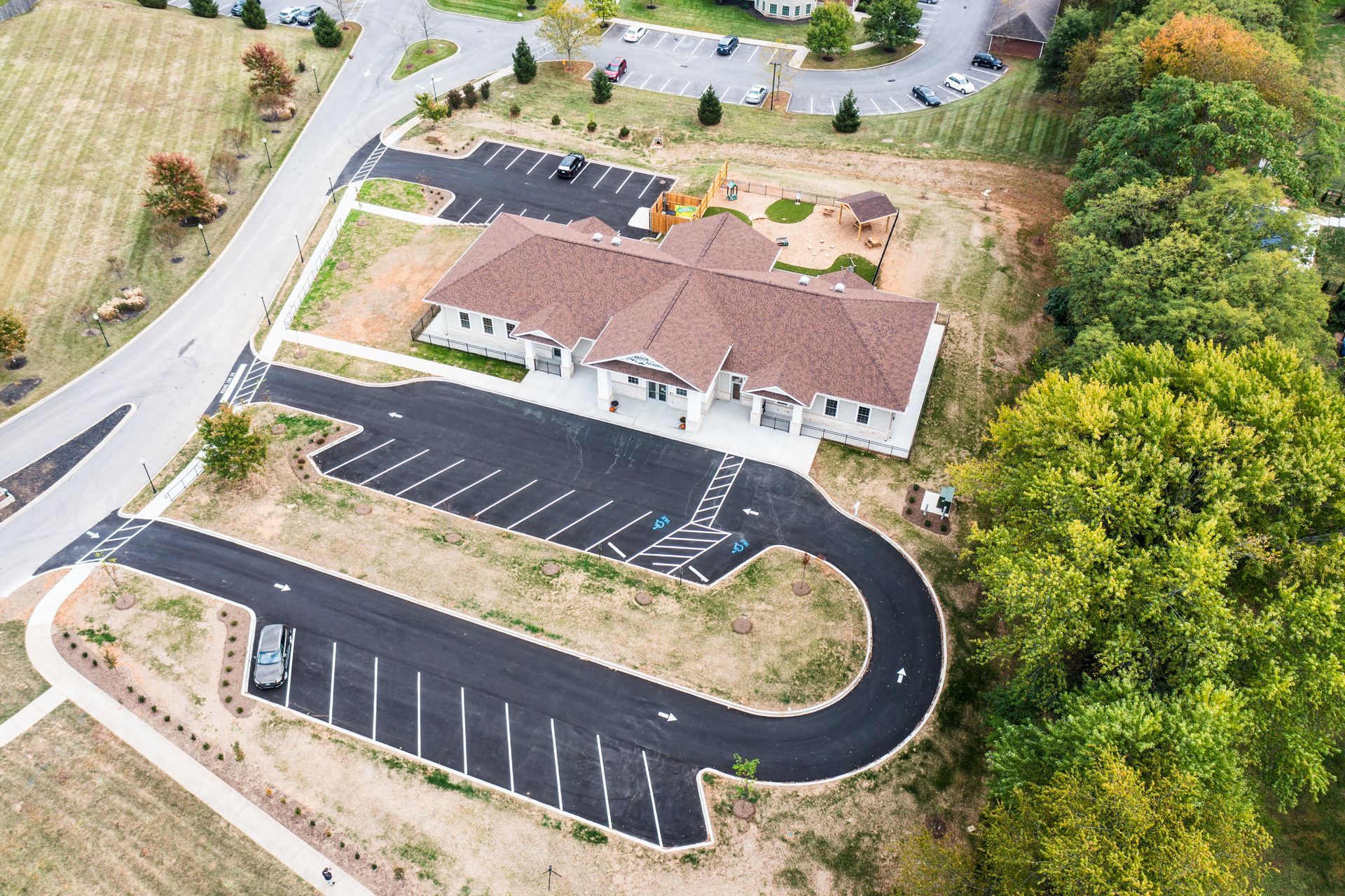 An aerial view of a parking lot with a house in the background