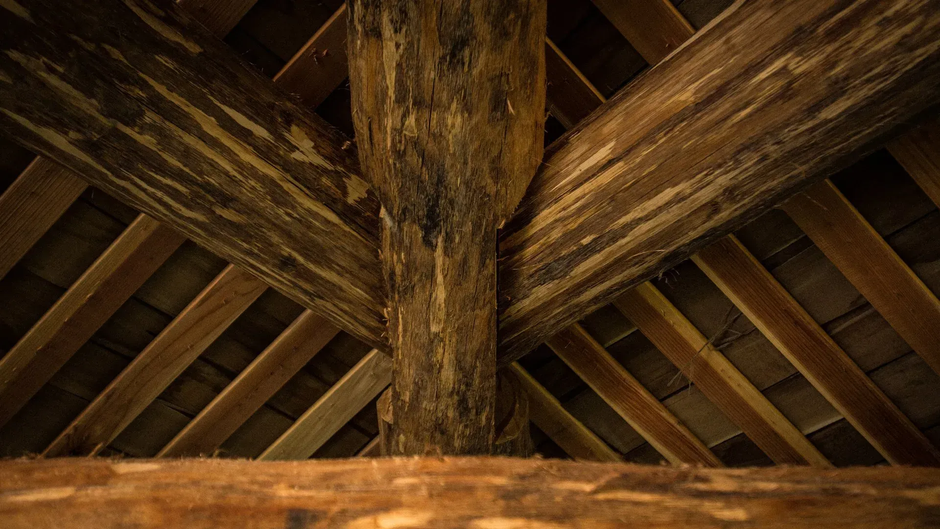 A close up of a wooden ceiling with a wooden post in the middle.