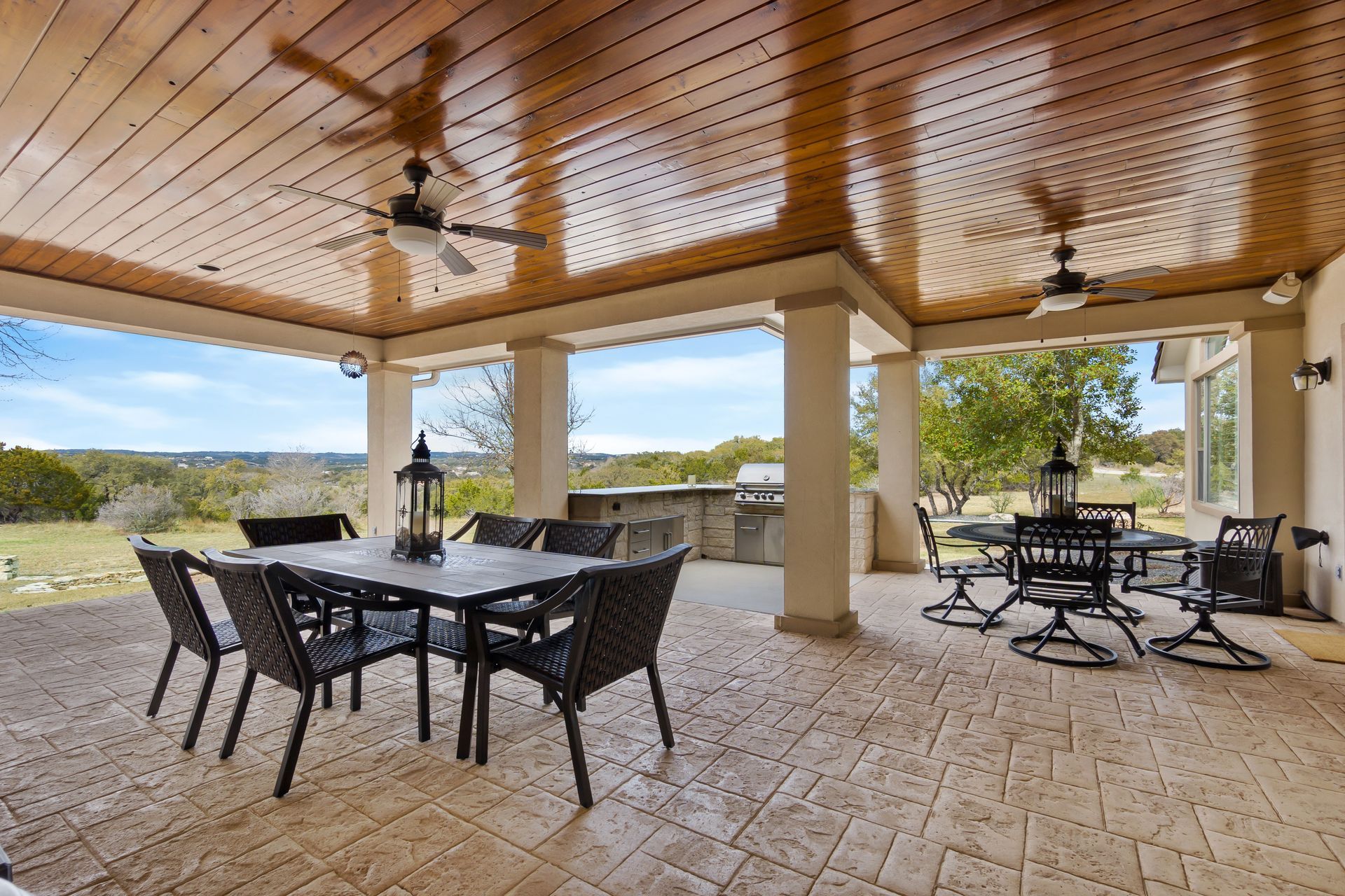 A well-designed and luxurious covered patio with outdoor seating and a kitchen at a residential home