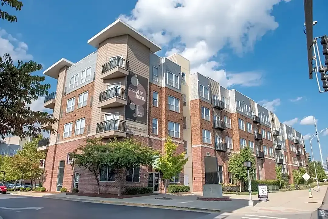 A large apartment building is sitting on the corner of a city street.