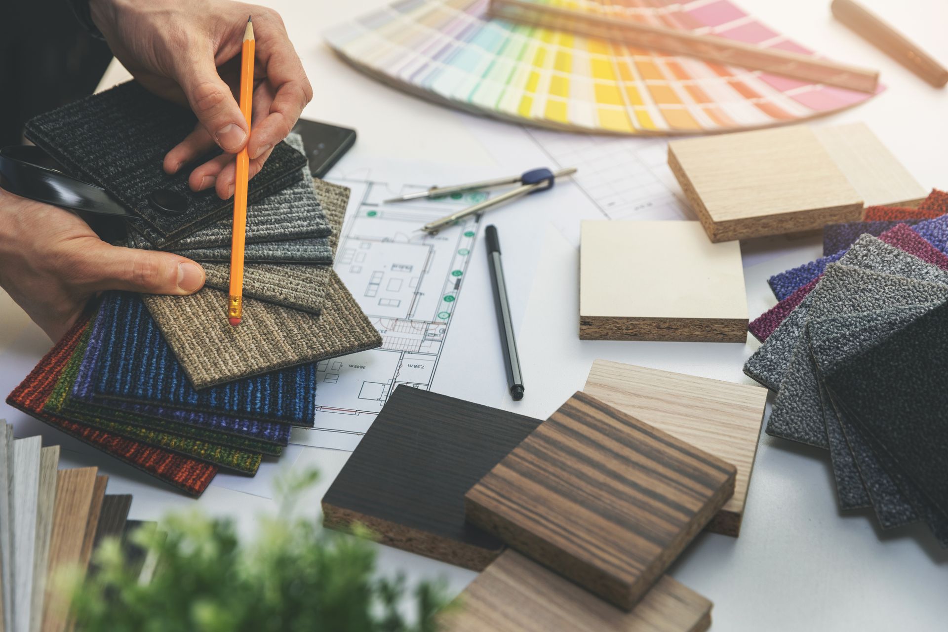 Interior designer holding flooring and color samples with a design layout. 