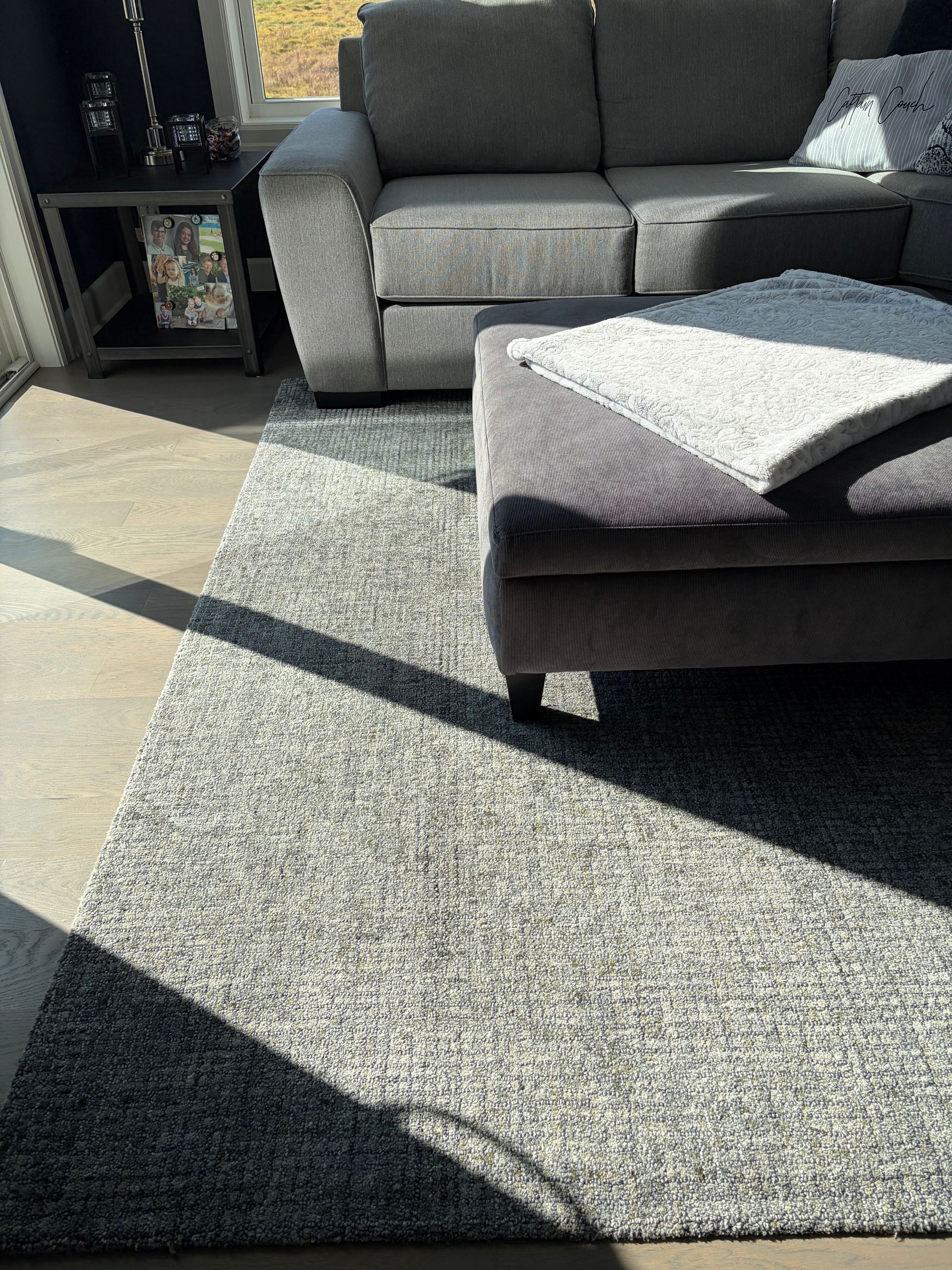 Spacious modern living room with gray walls, light sofa, rug, and armchair.