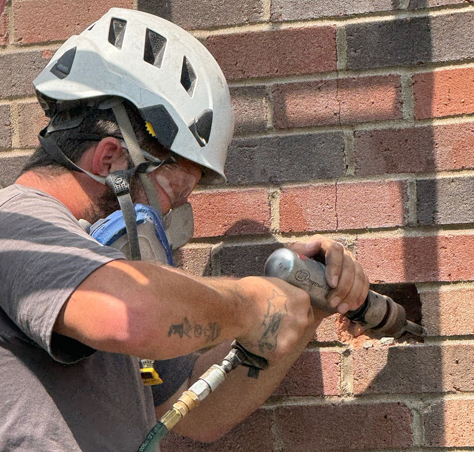 Certified chimney technician in a white helmet conducting masonry repair