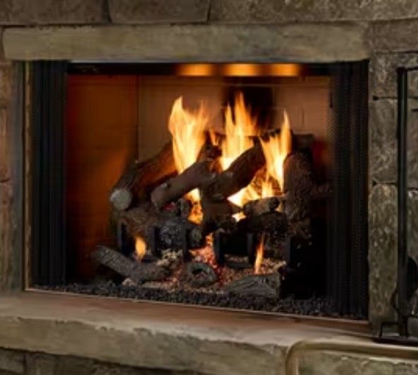 Stone fireplace with a burning log fire and glowing embers behind a glass screen