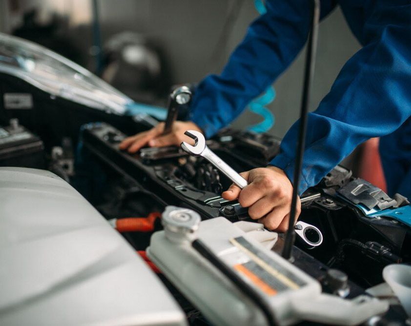 A Man Is Working On The Engine Of A Car With A Wrench — Buddha's Mechanical In Beaconsfield, QLD