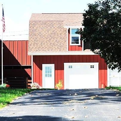 A red barn with a white garage door and an american flag