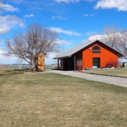 An orange house with a gray roof sits in the middle of a grassy field