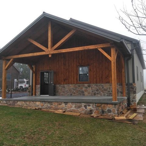 A small house with a wooden porch and a stone wall