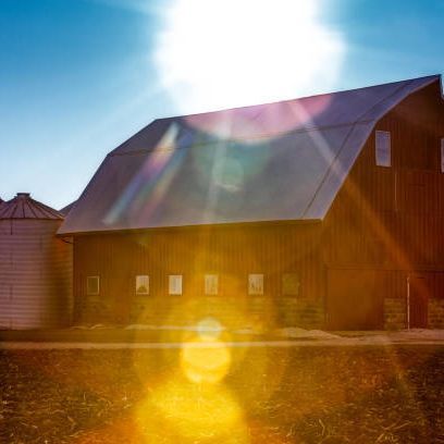 The sun is shining brightly on the roof of a barn.