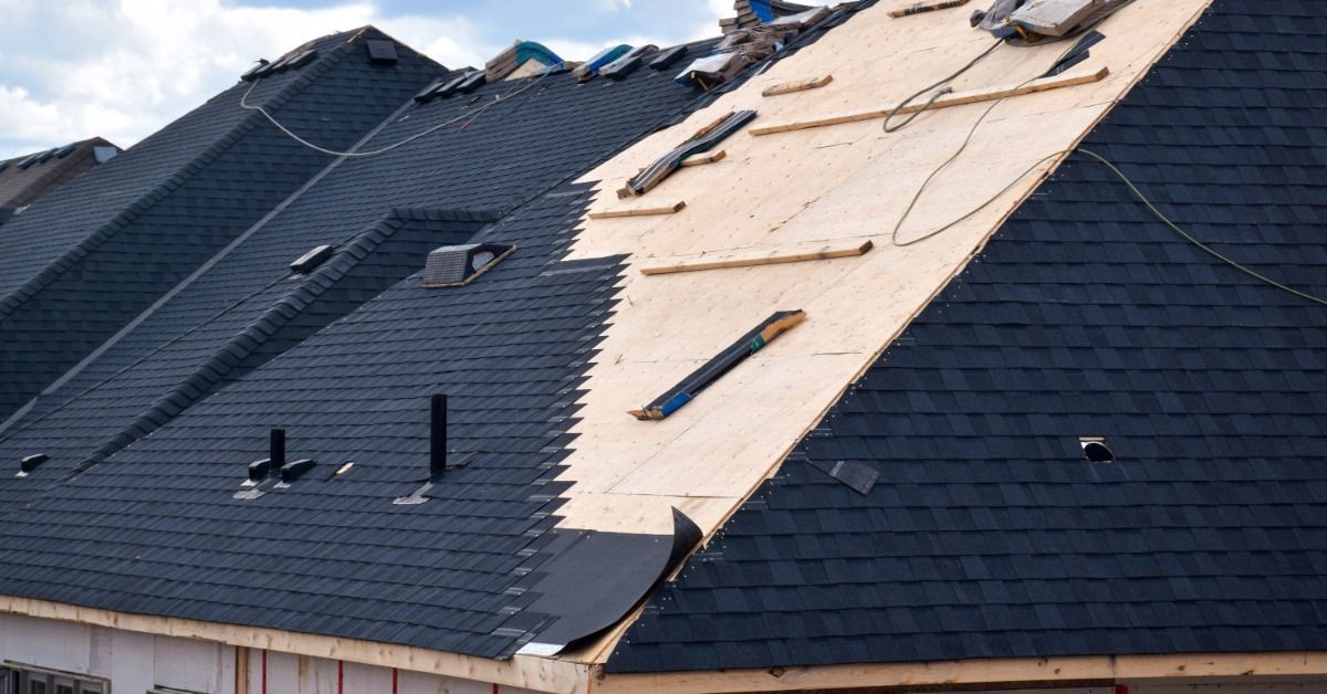 A partially completed roof installation on a large home, showing exposed roof decking beside newly installed shingles.