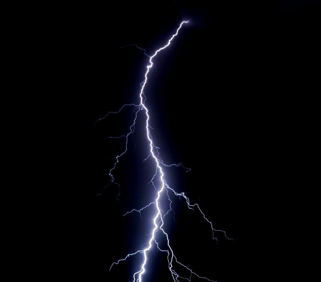 A lightning bolt is coming down in the dark sky.