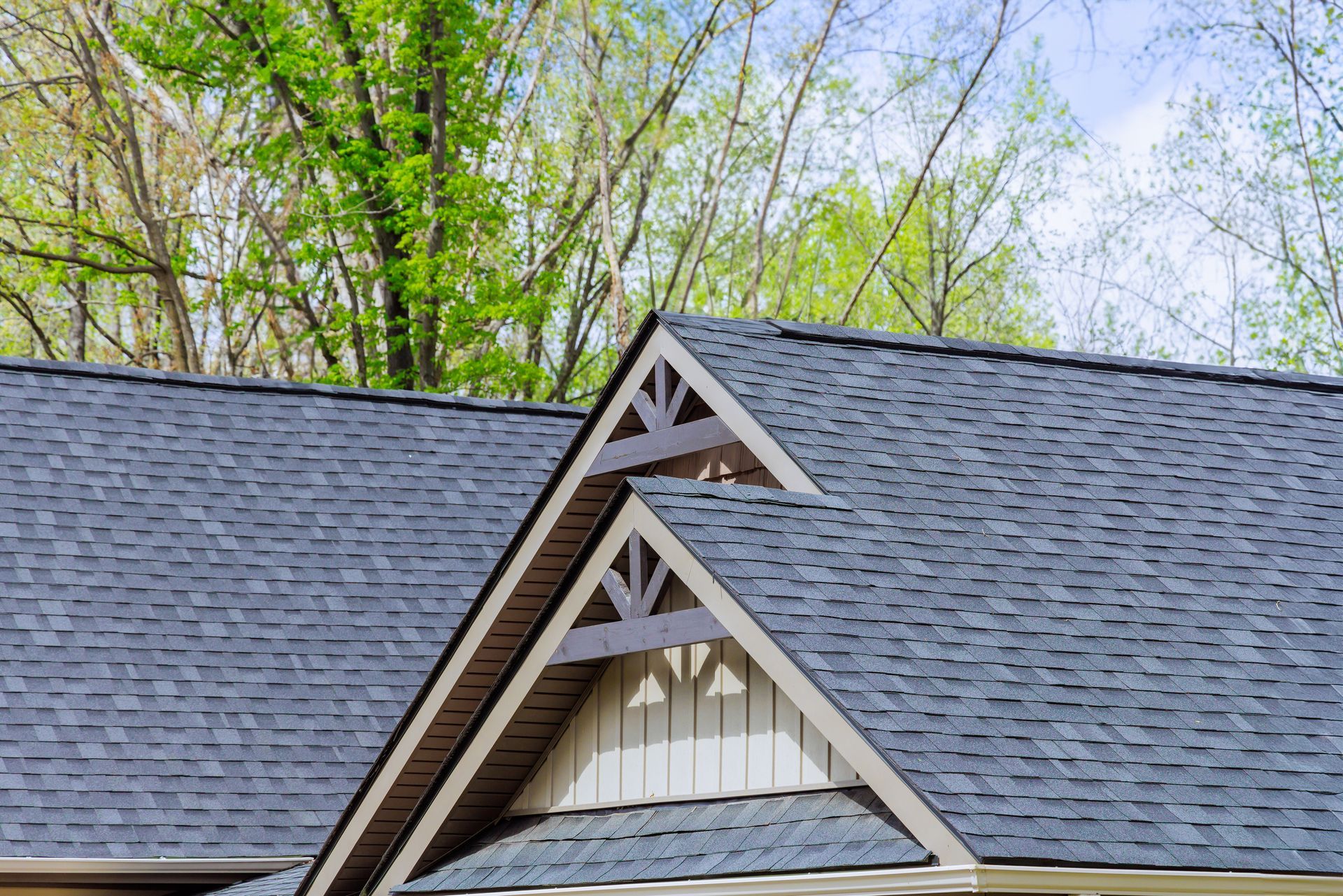 Aerial view of a damaged roof with missing shingles, exposing the underlayment, and debris nearby.
