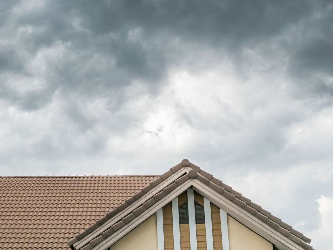The roof of a house with a cloudy sky in the background.
