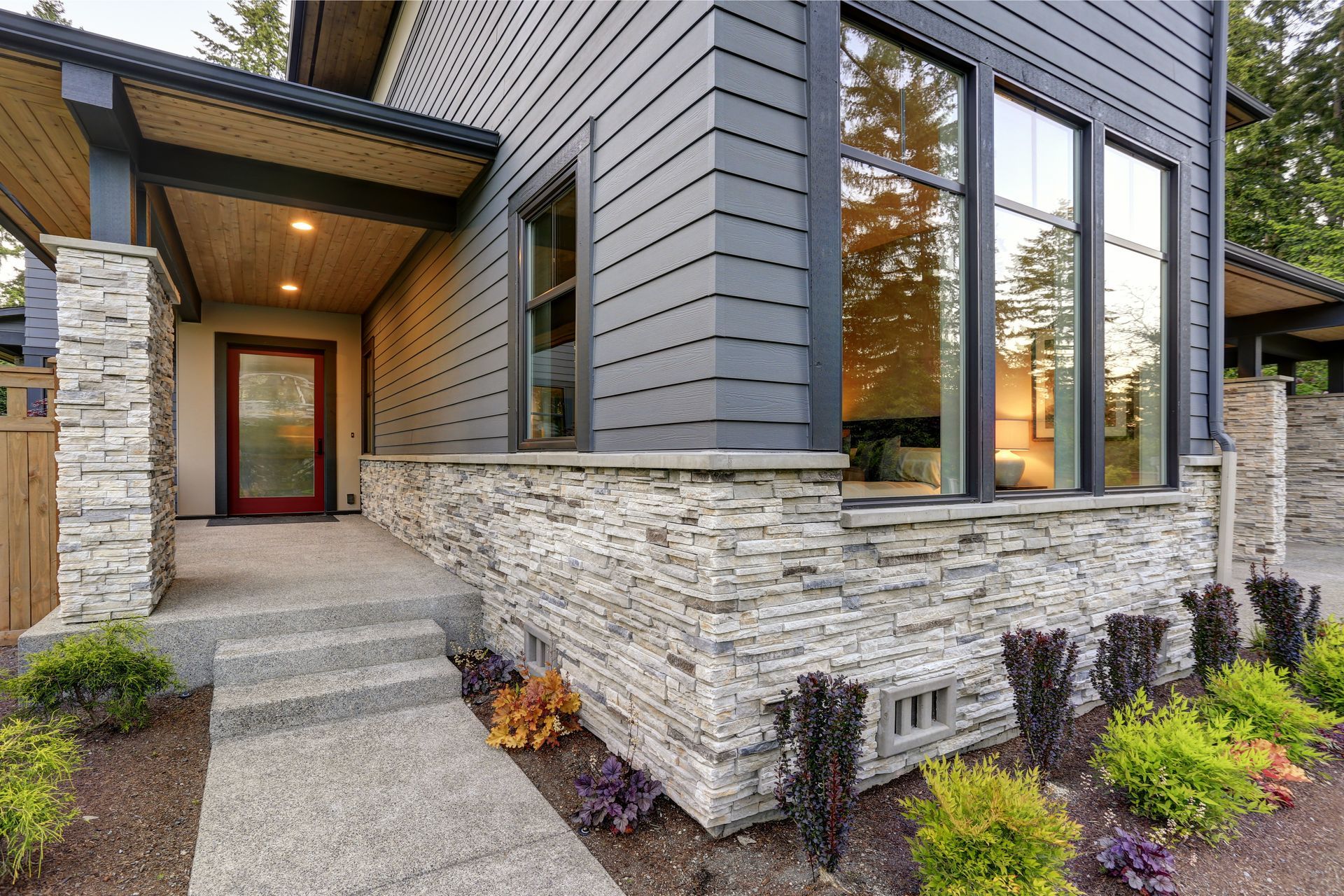 The front porch of a house with a stone wall and stairs leading up to it.
