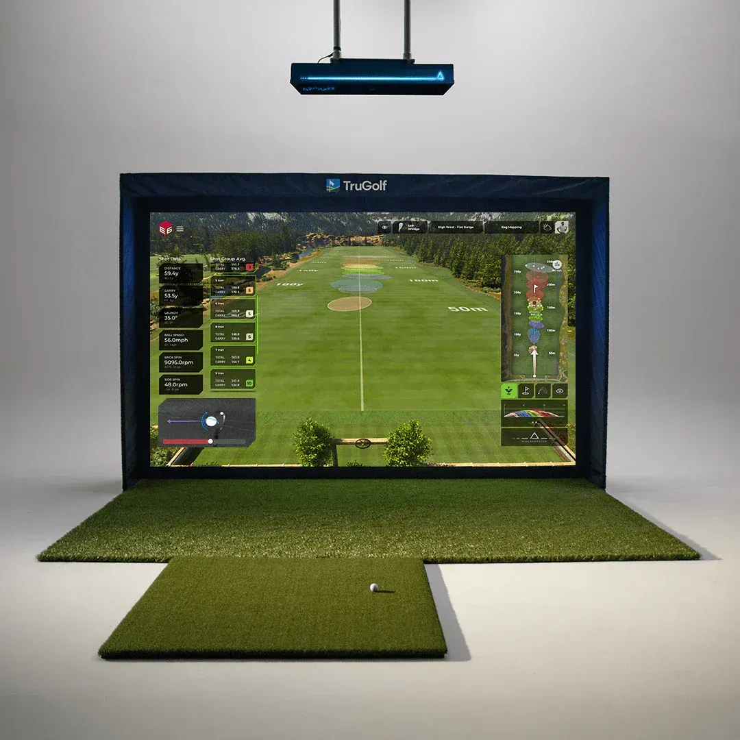 A TV displays a golf game on a green mat setup with artificial turf and a hanging light above.