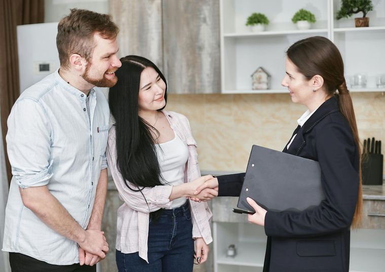 Couple shakes hands with a real estate agent inside a kitchen.