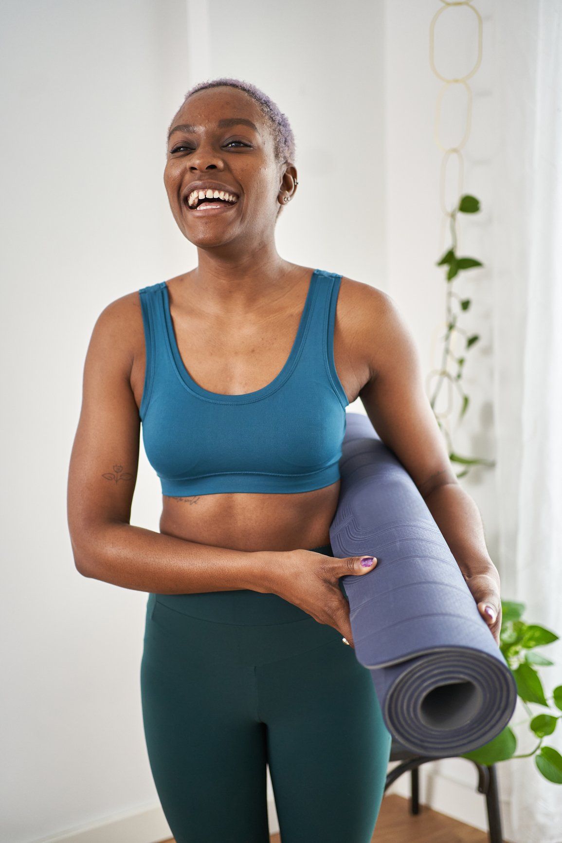 A women wearing workout cloth and holding a yoga mat.