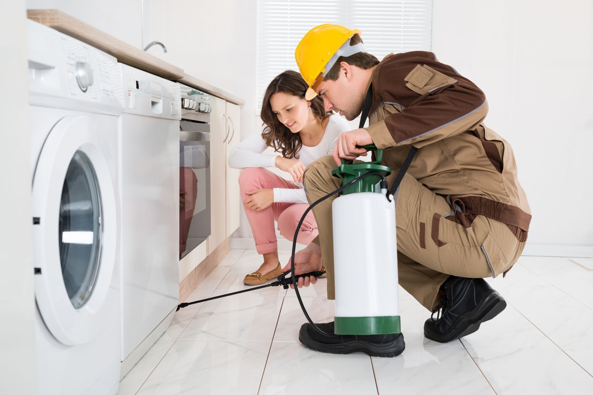 Technician and homeowner inspect a washing machine with a leak detector in a bright laundry room