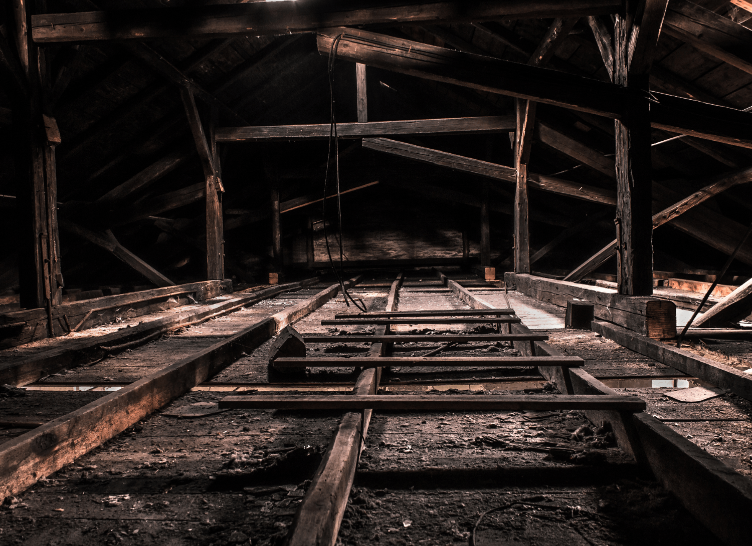 Rusty industrial interior with metal beams, rails, and a dark, decaying tunnel ceiling