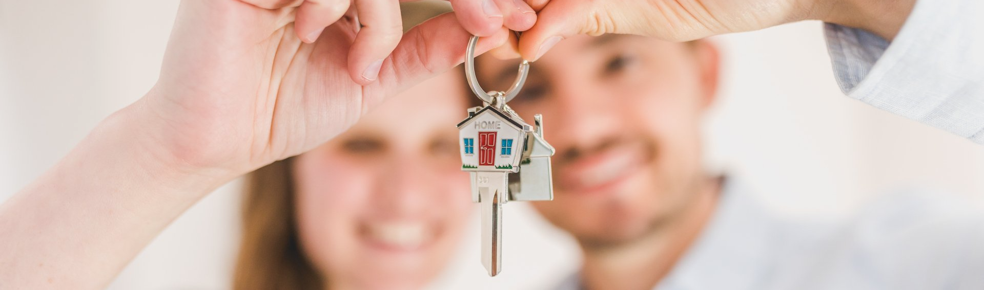 A man and a woman are holding keys to their new home.