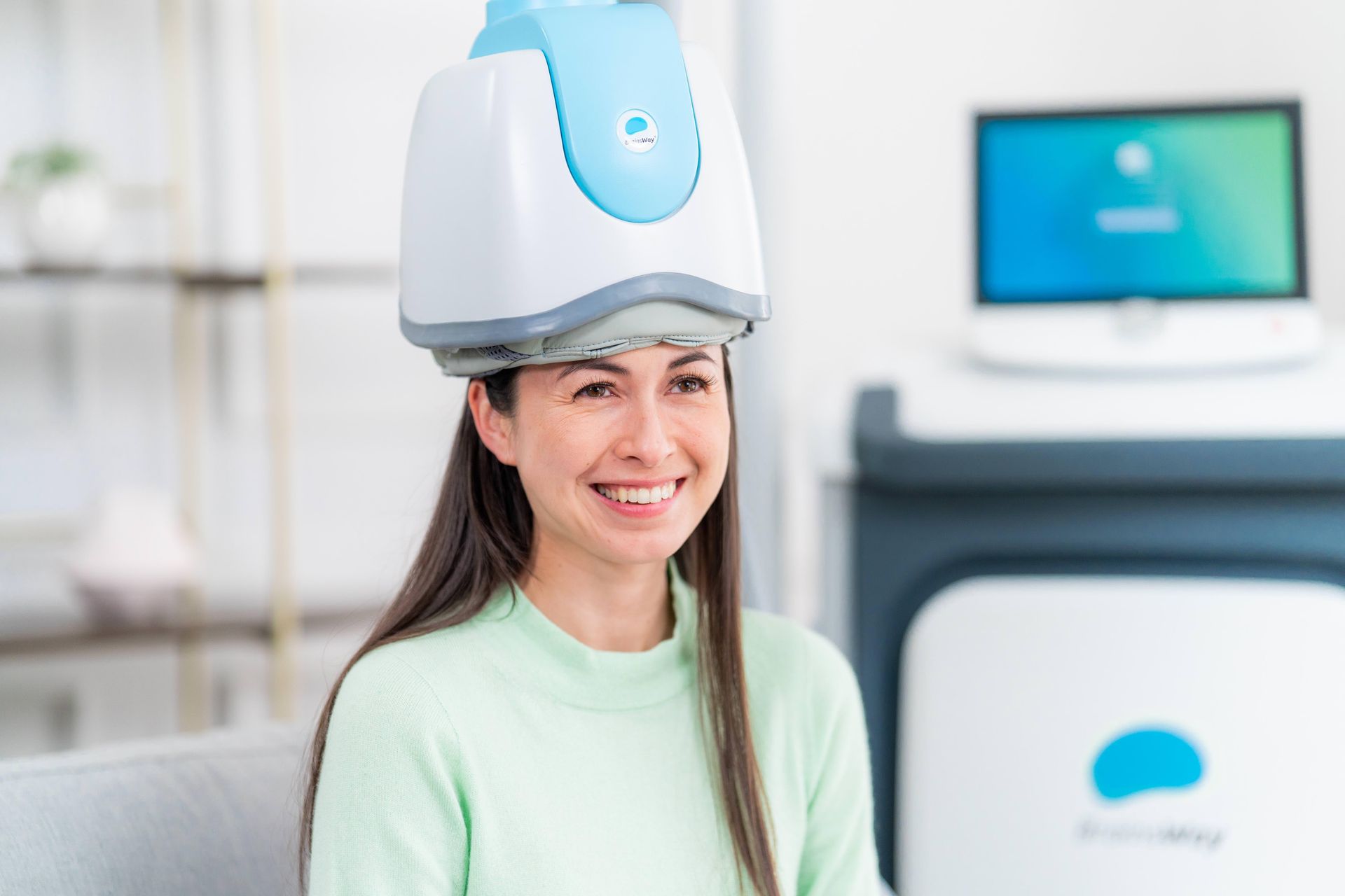 Woman wearing a head-mounted scanner in a medical clinic, smiling near a monitor