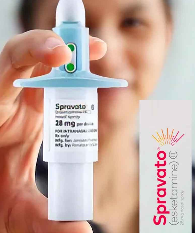 Person holding a Spravato nasal spray device close to the camera, label visible, blurred face in background