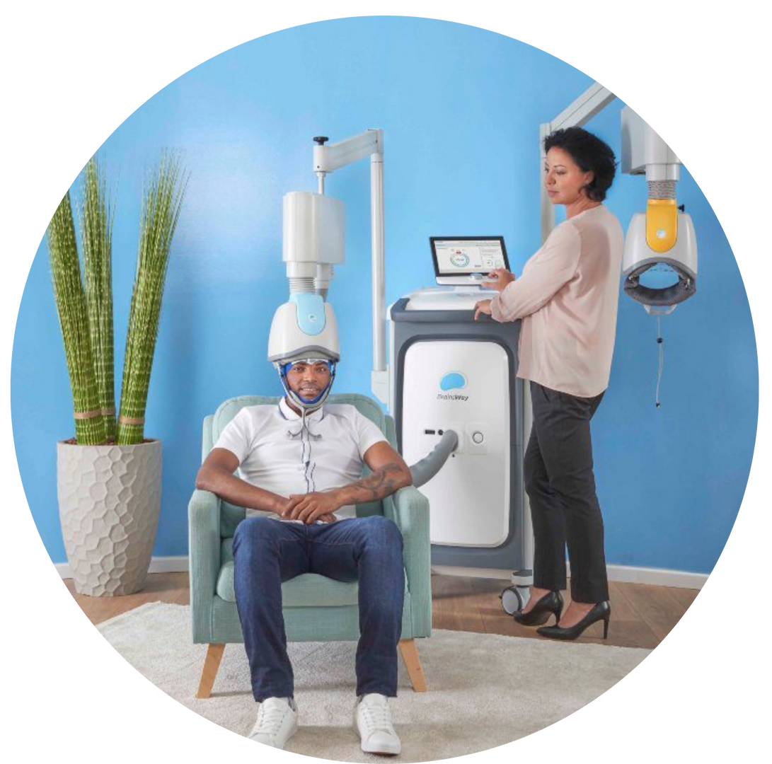 Person receiving dental treatment in a clinic, seated under a dental scanner beside a monitoring station.