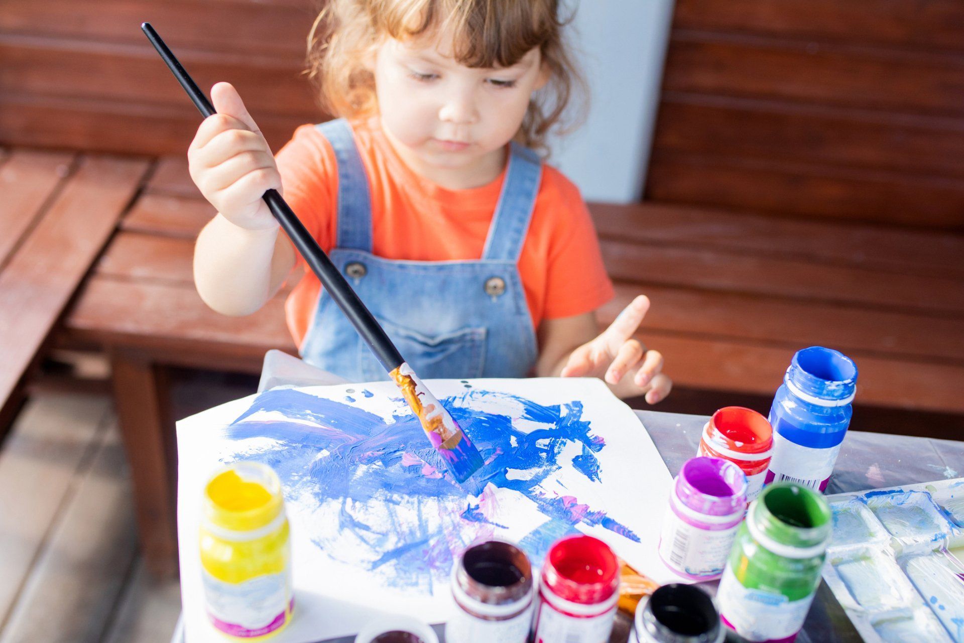Una niña está pintando con un pincel sobre un trozo de papel.