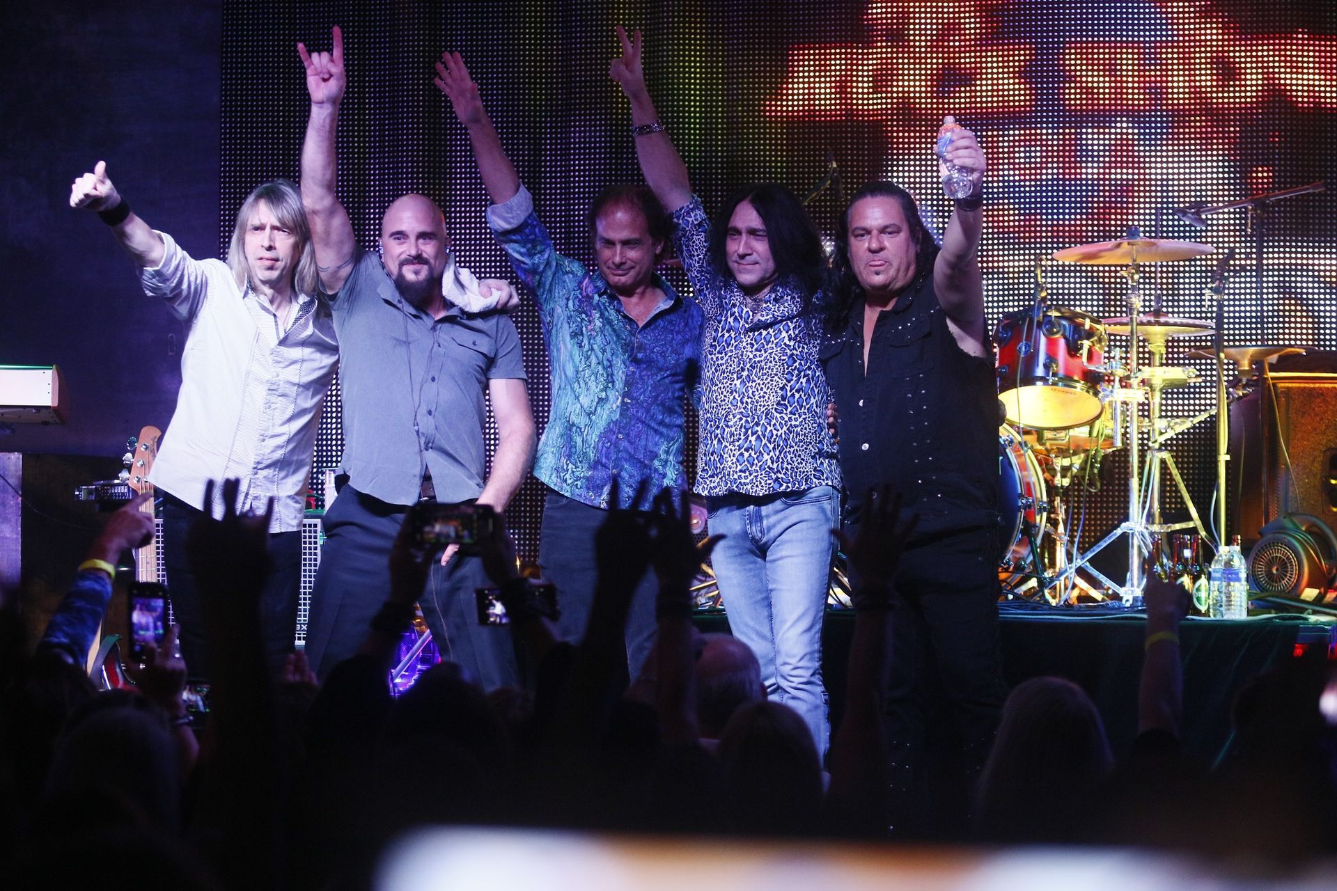 A group of men standing on a stage with their arms in the air