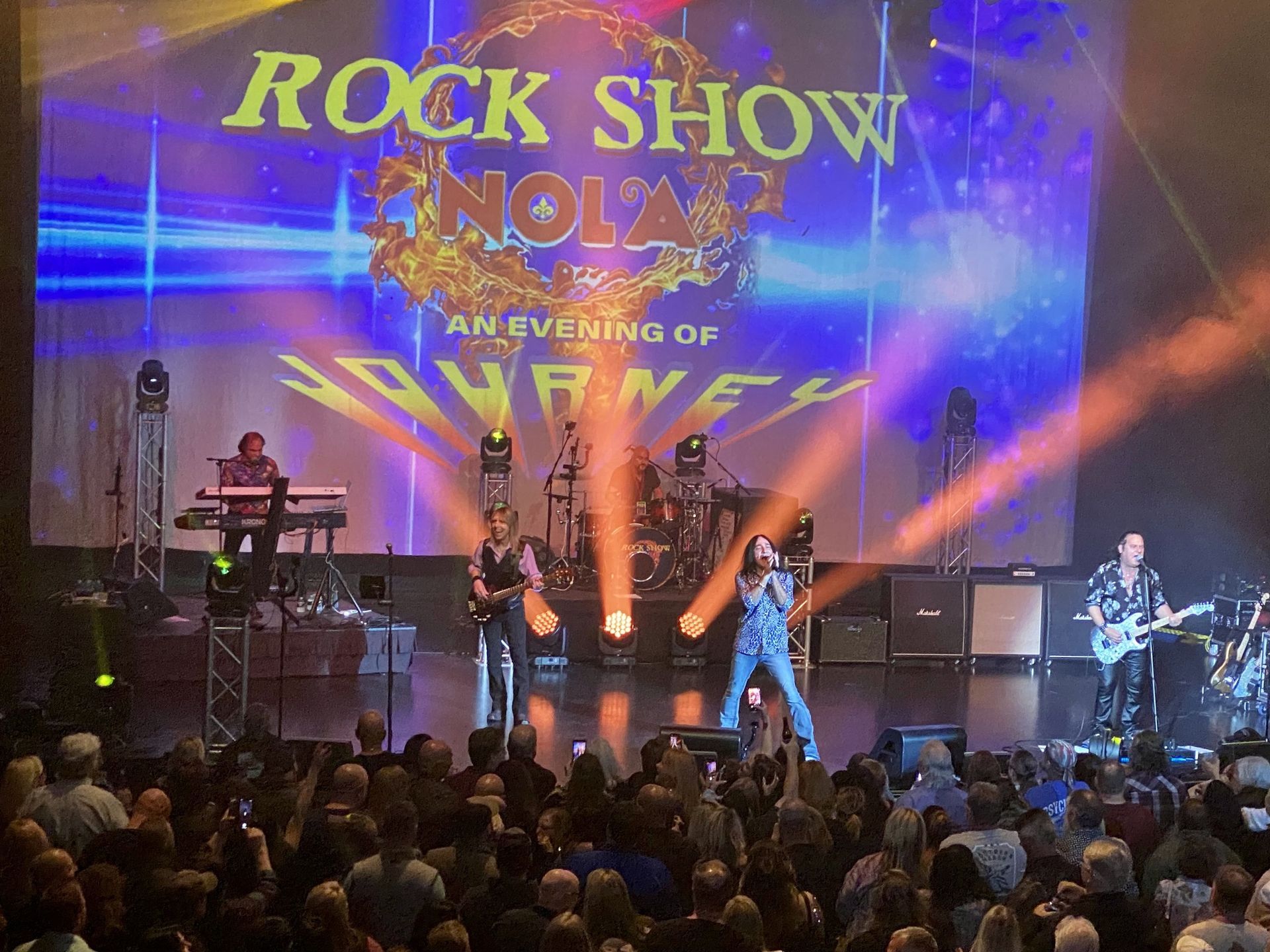 A rock show is taking place in front of a large crowd
