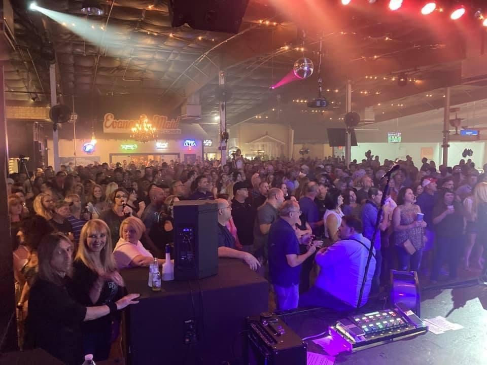 A large crowd of people are sitting in front of a stage at a concert.
