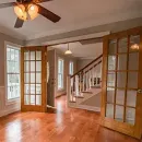 Bright kitchen under renovation with ladder, cabinets, tools, and a worker near the doorway
